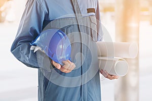 Engineer holding hard hat and blueprint