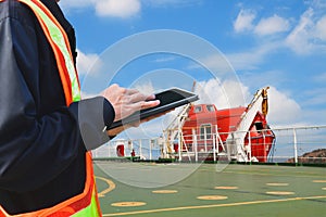 Engineer holding laptop and working with oil tanker freight ship in shipyard