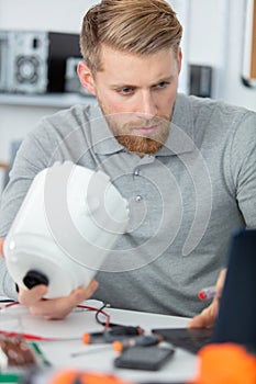 engineer holding parts and using laptop