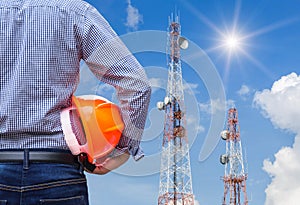 Engineer holding safety helmet with telecommunication tower pillars