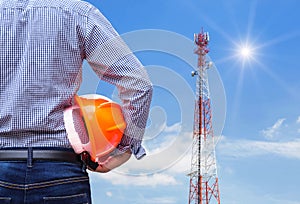 Engineer holding safety helmet with telecommunication tower pillars