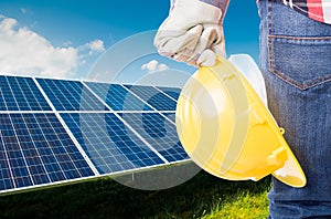 Engineer holding yellow helmet on solar power panels background
