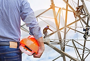 Engineer holding yellow safety helmet with electricians working on pylon construction tower