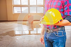 Engineer holding yellow safety helmet plastic and water leak drop interior office background