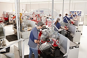 Engineer inspecting apprentices at their workstations photo