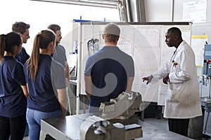 Engineer instructing apprentices at a whiteboard, close up