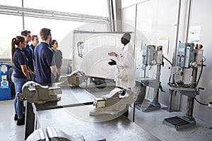 Engineer instructing apprentices at a whiteboard, side view