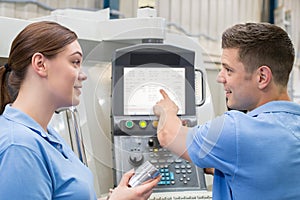 Engineer Instructing Female Apprentice On Use Of CNC Machine