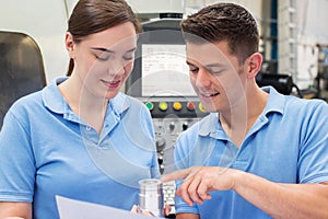 Engineer Instructing Female Apprentice On Use Of CNC Machine