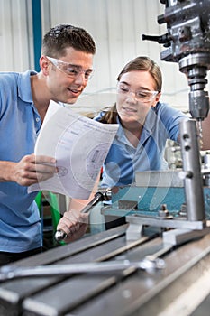 Engineer Instructing Female Apprentice On Use Of Drill