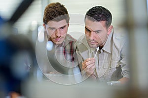 engineer instructs two apprentices at white board close up