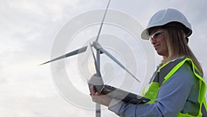 Engineer with a laptop near a windmill: analysis of the power of a wind turbine for green energy. Scientist at the