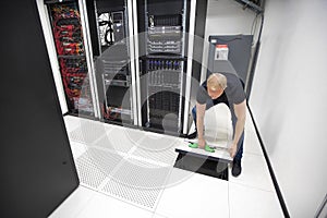 IT Engineer Lifting Floor Tile Using Suction Cups In Datacenter