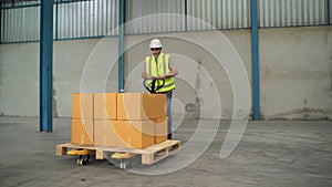 The engineer lifts the boxes to a cart and drags them in a warehouse.