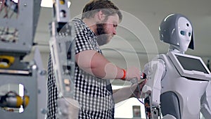 An engineer lowers down a robots arm to tighten shoulder nuts. 4K.