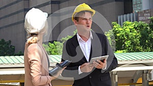 engineer man and business woman working with tablet and note book talking and checking plans together in construction site