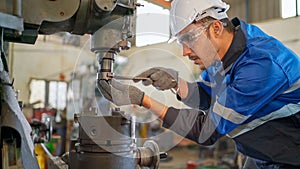 Engineer man checking the status of machine and used wrench to screw some part of equipment at CNC factory. Worker wearing safety