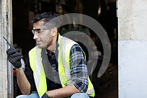 Engineer man or factory worker using walkie-talkie and feeling happy