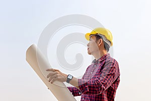 Engineer man holding blueprint checking and planning project at construction site, Man holding blueprint and looking into the sky