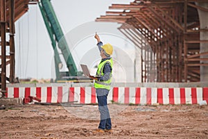 Engineer man with laptop checking project at infrastructure construction site, Foreman worker in building site