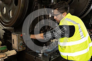 Engineer man pushing button on machine and controlling production