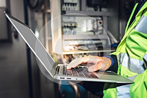 Engineer man using computer notebook for Checking the electrical system Of the machine