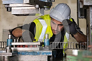 Engineer man wearing safety helmet and vest maintenance or repairing the machine by using wrench in the CNC metal factory.