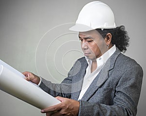 Engineer man worker with white safety uniform helmet  holding a drawing blueprint paper plan, construction process layout.