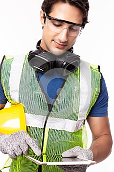 Engineer man working on digital tablet computer at worksite. Handsome young industrial worker were safety glove, protective