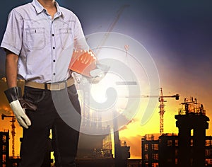 Engineer man working with white safety helmet against crane and building construction site use for civil engineering and construc