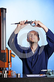 Engineer measuring with caliper against light