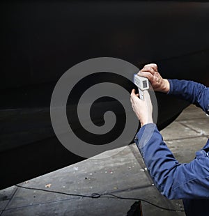 An engineer measuring the thickness of a steel hull