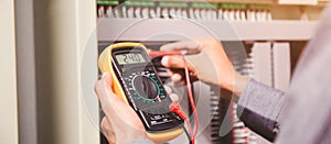 Engineer is measuring voltage or current by voltmeter in control panel