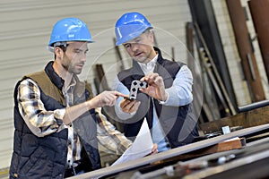 Engineer with mechanical worker checking on production quality