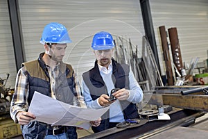 Engineer with mechanical worker checking on production quality