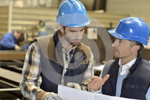 Engineer with mechanical worker checking on production quality