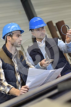 Engineer and mechanical worker discussing production