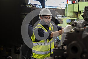 Engineer with monitor checking quality result of work. Man technician is working in a steel factory. Man worker in safety helmet