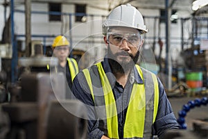 Engineer with monitor checking quality result of work. Man technician is working in a steel factory. Man worker in safety helmet w