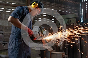 Engineer operating angle grinder hand tools in manufacturing factory - Mechanical engineering student using power tool with hot