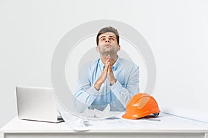 An engineer with orange hat praying for his work at the office