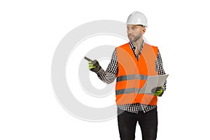Engineer in orange reflective waistcoat and white helmet is standing with documents and pointing to the side