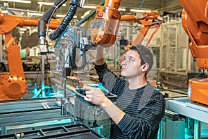 Engineer performs maintenance of industrial robot in a factory