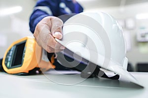 The engineer picks up the white helmet placed on the office desk with a blurred background