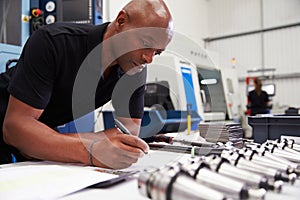 Engineer Planning Project With CNC Machinery In Background