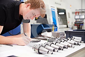 Engineer Planning Project With CNC Machinery In Background