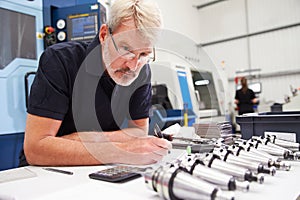 Engineer Planning Project With CNC Machinery In Background