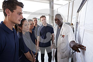 Engineer pointing to whiteboard while training apprentices photo