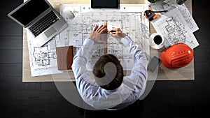 Engineer preparing building drawing for tender, making corrections, top view