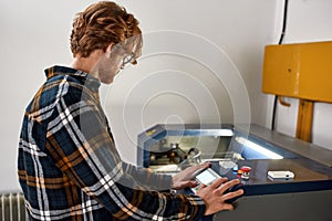 Engineer pressing button on panel of CNC machine
